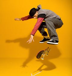 a man flying through the air while riding a skateboard in front of a yellow background