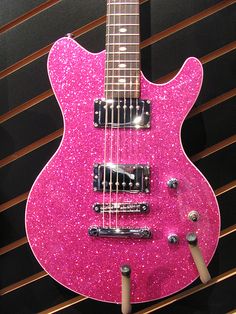 a pink guitar is sitting on display