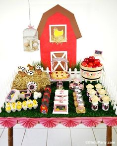 a table filled with lots of food on top of a grass covered field next to a red barn