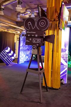 a camera set up on a tripod in front of a stage with yellow drapes