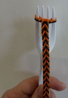 a hand holding an orange and black braided plastic fork