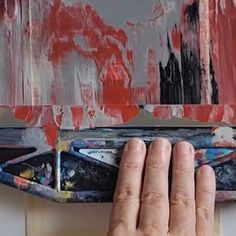 a person holding their hand on top of a piece of art that has been painted