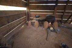 an open fire pit in the middle of a room with wooden walls and flooring