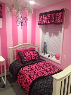 a bedroom decorated in pink and black with a chandelier