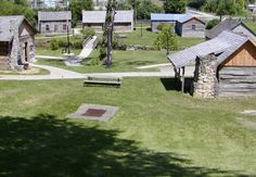 an aerial view of small cabins and picnic tables in a park with grass, trees, and stone buildings