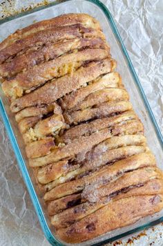 a loaf of bread sitting on top of a glass baking pan covered in powdered sugar