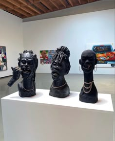 three busturines are on display in an art gallery