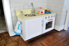 a white toy kitchen with sink and oven