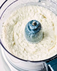 a food processor filled with white powder and blue stuff in it's bowl on top of a counter