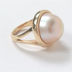 a close up of a pearl ring on a white surface