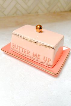 a pink and gold butter me up container