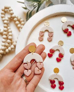 a person is holding several pairs of earrings in their hand next to other pieces of jewelry