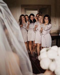 a group of women standing next to each other in front of a bride and groom