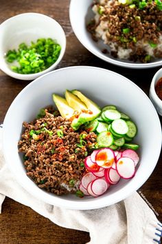 two bowls filled with rice, meat and veggies on top of a wooden table