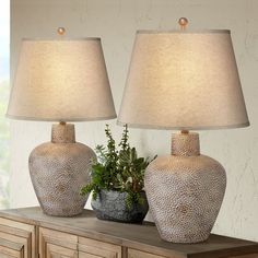 two vases sitting on top of a dresser next to each other with a plant in the middle