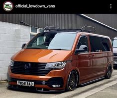 an orange van parked in front of a building with two other vans behind it on the street