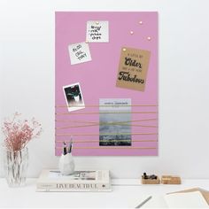 a pink bulletin board with pictures and post it notes attached to the back of it