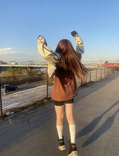 a woman standing on the side of a road with her legs in the air