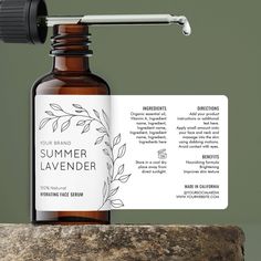 a bottle of summer lavender essential oil sitting on top of a rock next to a business card