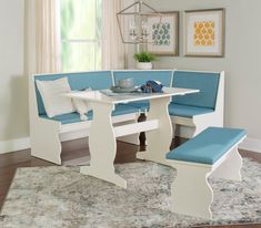 a white table with blue cushions and bench in front of a large rug on the floor