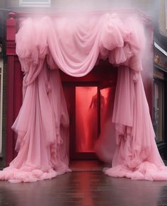 an open red door with pink fabric draped over it and fog coming from the doorway