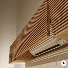 a white air conditioner sitting on top of a wooden shelf above a tiled wall