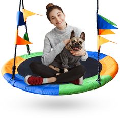 a woman sitting on a trampoline with a dog in her lap and smiling at the camera