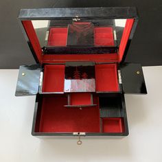 an open red and black jewelry box sitting on top of a table