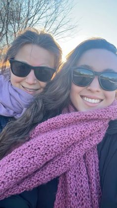 two women wearing sunglasses and scarfs posing for the camera with their arms around each other