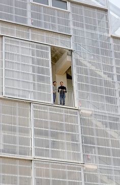 two men standing in the window of an apartment building