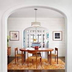 an archway leads into a dining room with white walls and wood flooring, along with wooden chairs