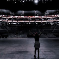 a woman standing in an empty stadium with her arms up and hands raised above her head