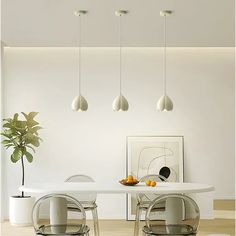 a white dining room table with four chairs and a potted plant on the side