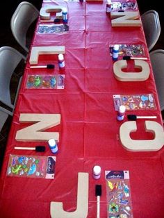 a red table topped with lots of pictures and letters on top of each other next to chairs