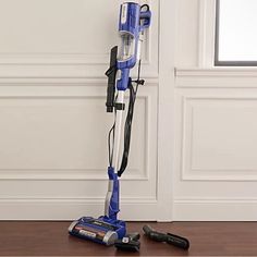 a blue and white vacuum is on the floor next to a pair of screwdrivers