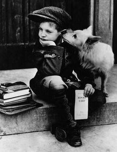 a young boy sitting on the steps next to a small dog and holding a book