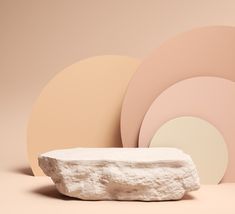 a white rock sitting in front of some pink and yellow circles on a beige background