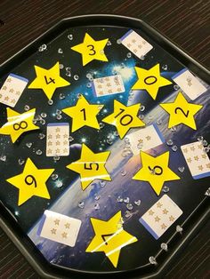 a black tray with yellow stars on it and numbers in the middle, surrounded by water droplets