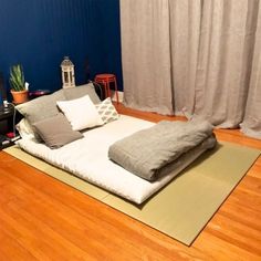 a bed sitting on top of a hard wood floor next to a window with curtains