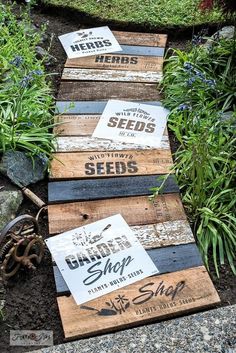 three wooden signs sitting on top of a pile of dirt next to grass and flowers