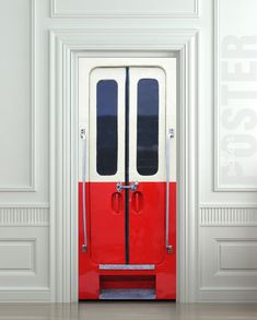 a red and white door with two black doors on each side in an empty room