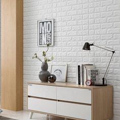 a living room with white brick walls and wooden furniture on the floor, along with a large window