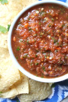 a white bowl filled with salsa next to tortilla chips on a blue and white plate