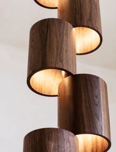 three wooden lamps hanging from the ceiling with dim lights on each lamp shade and wood grain coverings