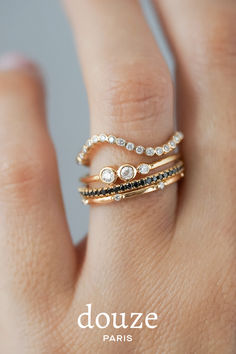 a woman's hand wearing a gold ring with black and white stones on it