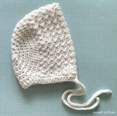 a crocheted white hat on top of a blue surface with a string attached to it