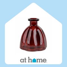 a red glass vase sitting on top of a blue and white sign that says at home