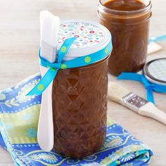 two jars filled with brown liquid and toothbrushes on top of a blue napkin