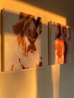 three pieces of art are hanging on the wall next to each other, one is orange and white