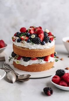 a cake with berries and whipped cream on top sitting on a plate next to other desserts